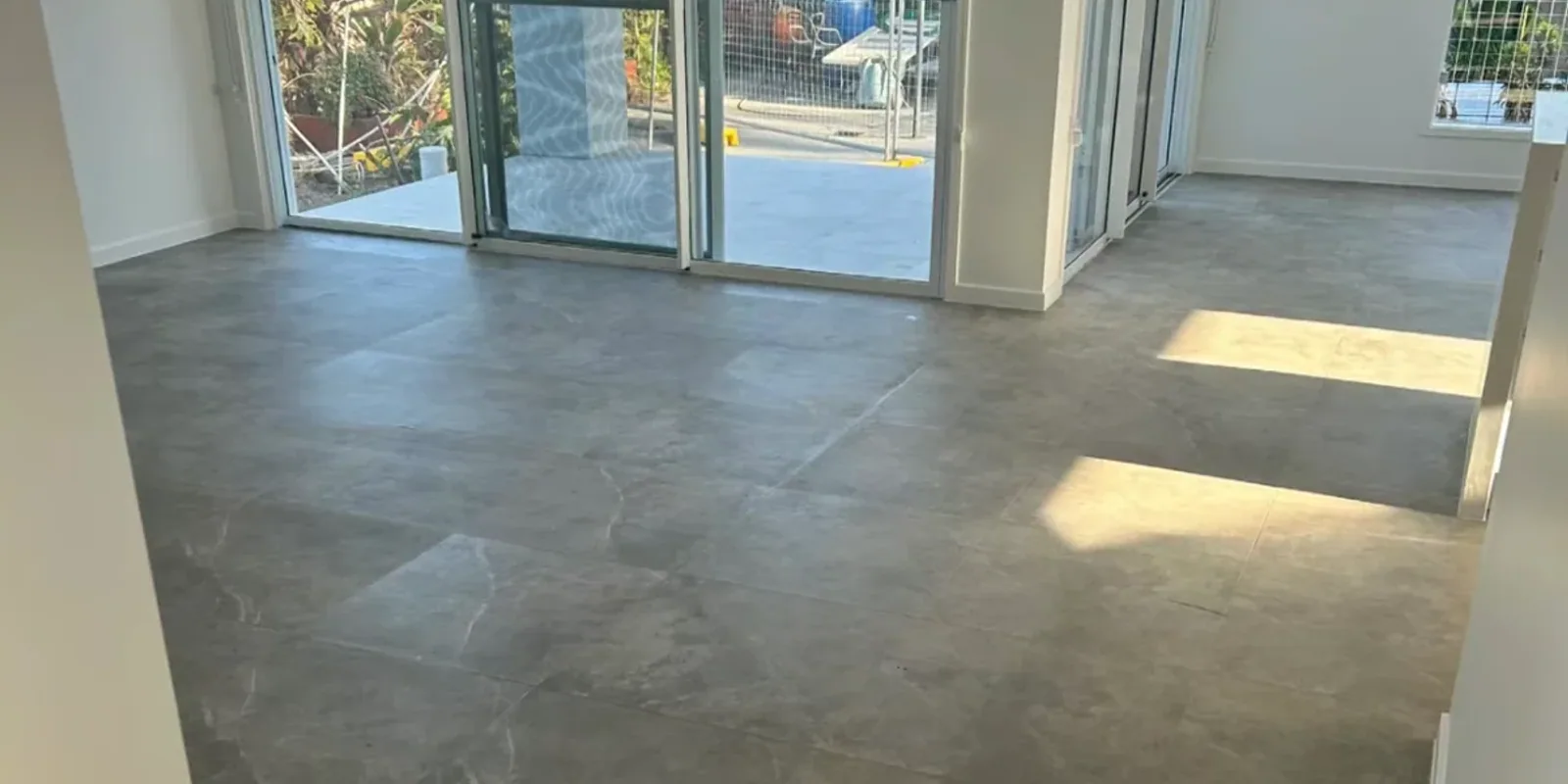 Large-format grey floor tiles installed through an open-plan living area.