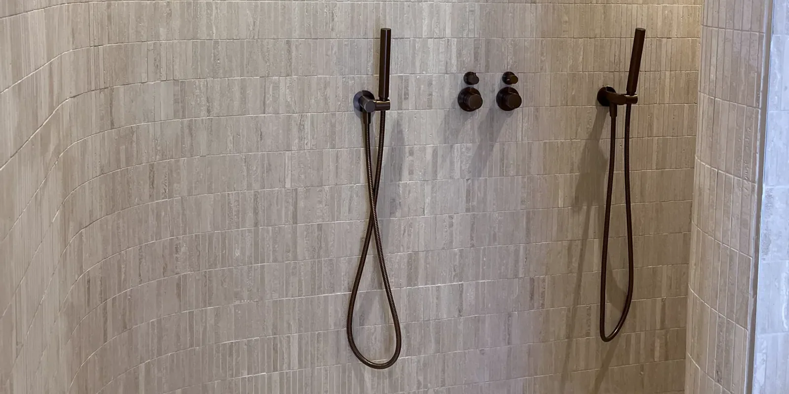 Completed tiled shower with curved feature walls and dark bronze fittings.