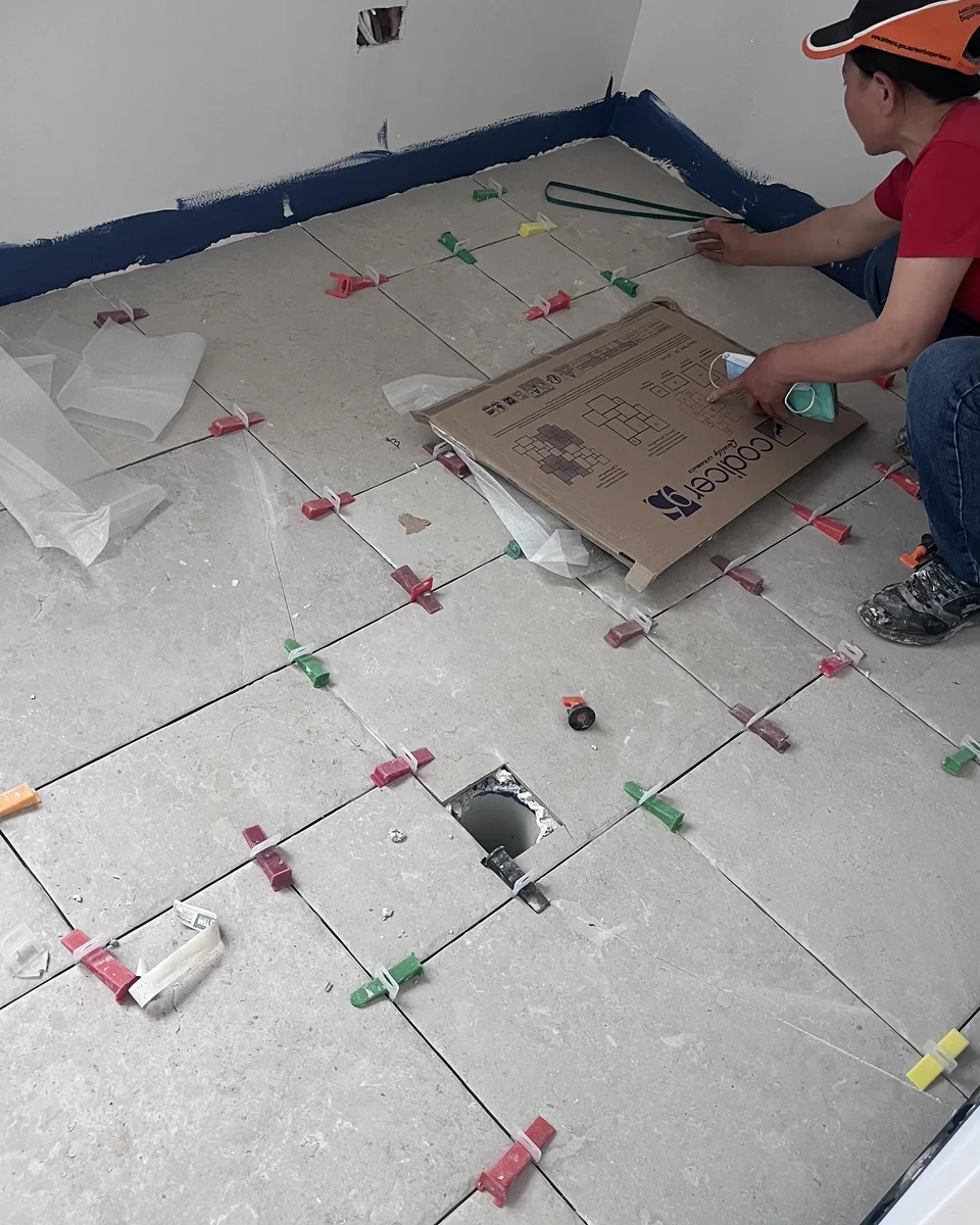 Tiler laying large-format floor tiles during installation.