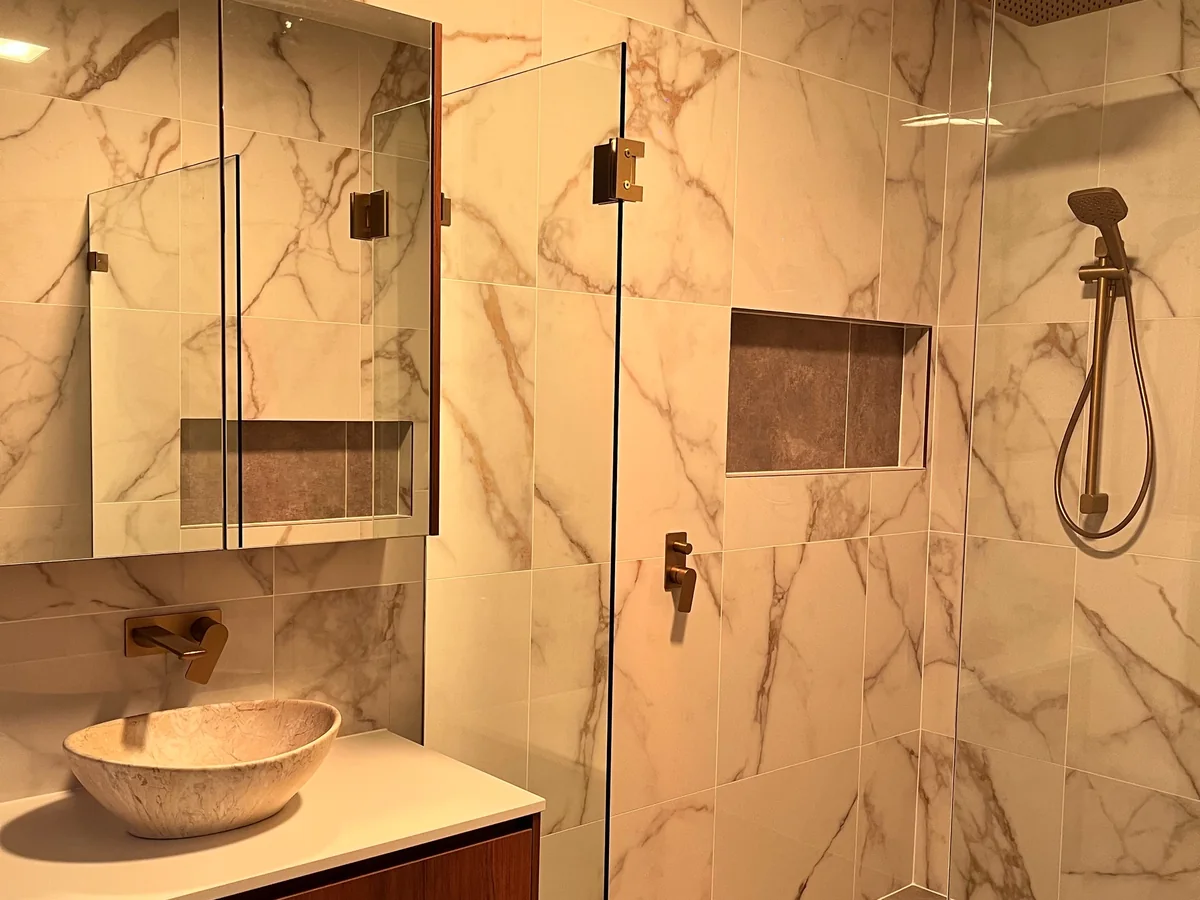 Bathroom tiling project with marble-look wall tiles and walk-in shower.