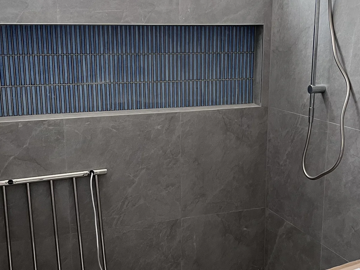 Grey bathroom tiling with a feature niche and shower fitting set-out.